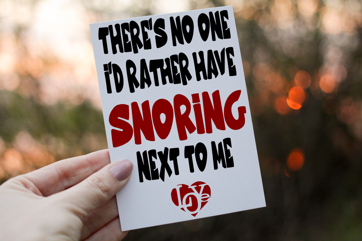 Photograph of an anniversary card showing bold snoring joke lettering on a white card.
